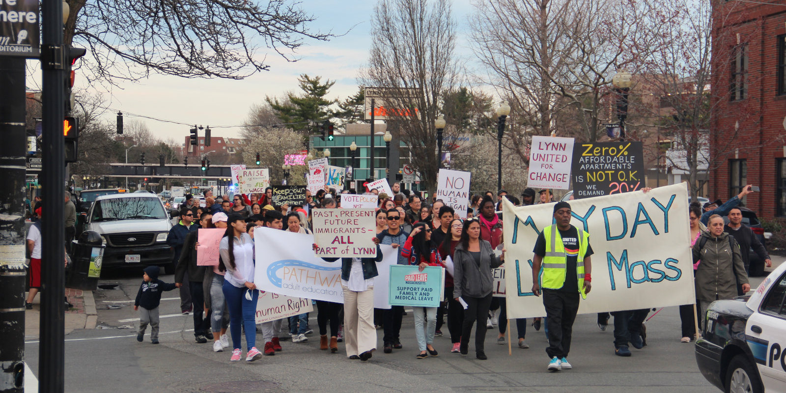 Photo of Lynn, MA May Day march - large crowd marching in street with protest signs.